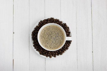 expresso coffee in a white mug on a white wooden background coffee beans around sugar and sweets