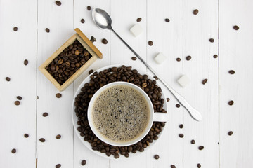 expresso coffee in a white mug on a white wooden background coffee beans around sugar and sweets