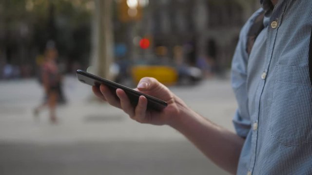 Man using touch Mobile Phone outdoor, close up, man walking with cell phone on city street people and cars background, crossroad use application