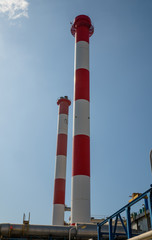 Fototapeta premium Electric Power Plant Chimneys. Two industrial chimneys from electric power. Blue sky in background. Stock Image