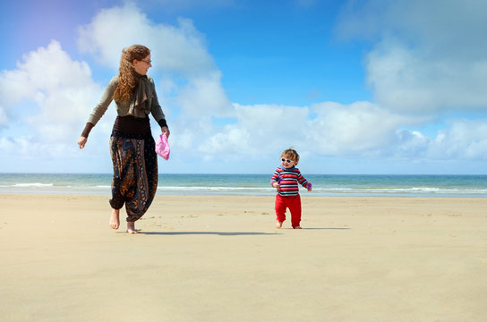 beautiful little girl playing on the beach with her mom