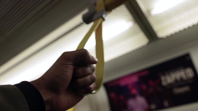 Adult Male Hand Grabbing Yellow Hand Strap On The London Underground. Low Angle