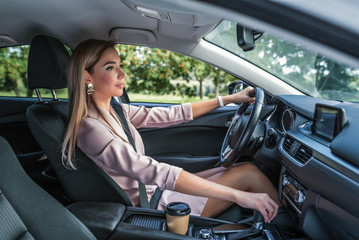 Beautiful girl business lady summer city car. Reversing, looking rearview mirror, engaging reverse gear, traffic jam parking lot. Car rental, car sharing. Automatic transmission. Autumn day nature.
