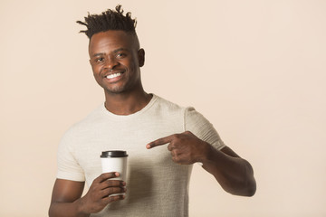 handsome young african man on a beige background with a glass of coffee in his hands