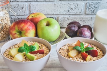 Sweet delicious healthy breakfast. Porridge with apples and plums on the kitchen table.