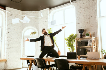 Young caucasian businessman having fun dancing break dance in the modern office at work time with gadgets. Management, freedom, professional occupation, alternative way of working. Loves his job.