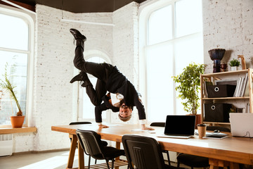 Young caucasian businessman having fun dancing break dance in the modern office at work time with...