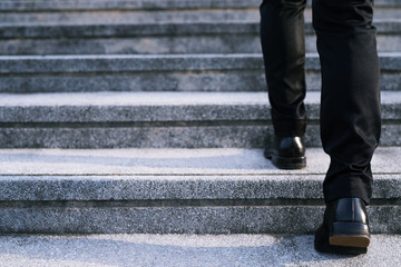 modern businessman working  close-up legs walking up the stairs in modern city. in rush hour to...