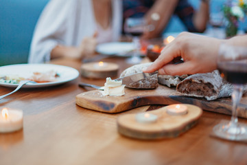 Friends and family gathered for picnic dinner for Thanksgiving. Festive young people celebrating life with red wine, grapes, cheese platter, and a selection of cold meats