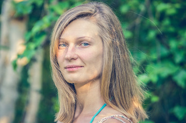 Naklejka premium Portrait of a young beautiful smiling woman on nature background