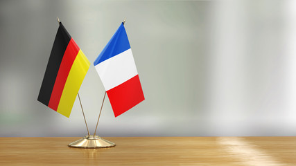 French and German flag pair on a desk over defocused background 