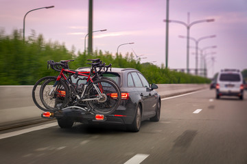 Car transports bicycles on a rack on highway in early morning