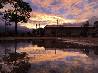 sunset sky and clouds at park near typhoon while reflecting in puddle