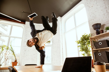 Young caucasian businessman having fun dancing break dance in the modern office at work time with...