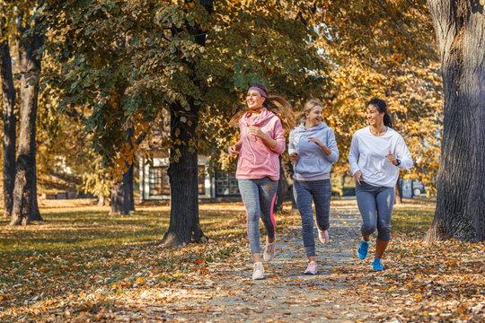 Group of female friends jogging at the city park.Autumn season.