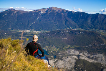 Fototapeta premium Traveler man sitting on a hill of beautiful alpine landscape