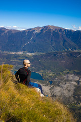Fototapeta premium Traveler man sitting on a hill of beautiful alpine landscape
