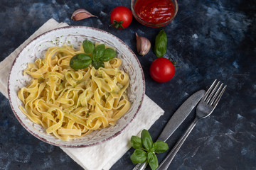 Italian pasta, spaghetti with avocado, spinach, basil, cream, cheese. Vegetarian vegetable pasta. Spinach with noodles. On a light background. Nearby are cherry tomatoes, olive oil. Copy space. 