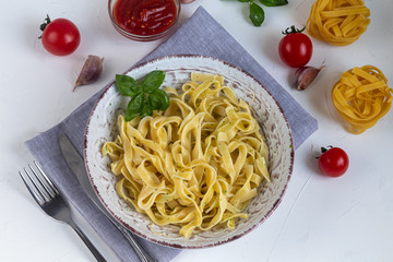 Italian pasta, spaghetti with avocado, spinach, basil, cream, cheese. Vegetarian vegetable pasta. Spinach with noodles. On a light background. Nearby are cherry tomatoes, olive oil. Copy space. 