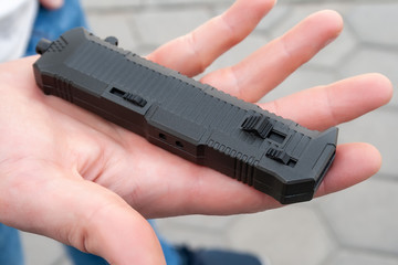Closeup view of a black charged pocket folding knife lying on the palm