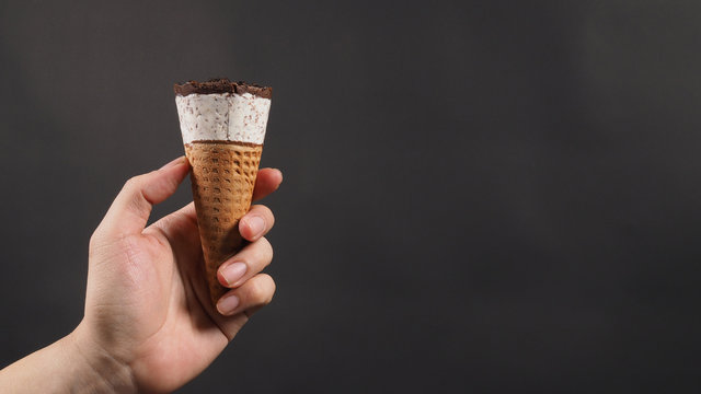 Hand Is Holding Ice Cream Cone With Black Background.