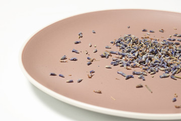 Dried blue lavender flowers with ceramic brown plate white background half view