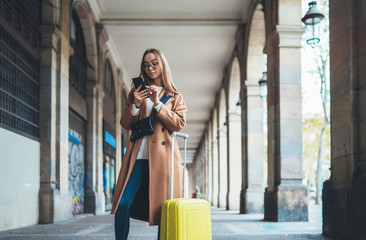 Tourist suitcase holding smart mobile phone. Girl travels in Barcelona. Holiday concept in Spain...
