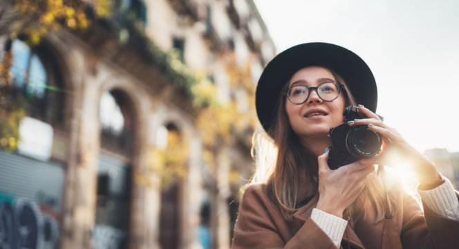 Photographer in glasses photo camera. Tourist portrait. Smiling girl in hat in Barcelona holiday. Sunlight flare street in europe city. Traveler hipster shooting architecture, copy space mockup