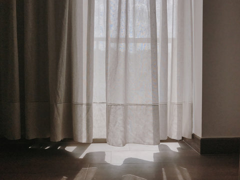 Sunlight shining through white curtain on window