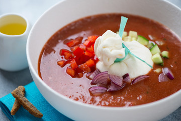 Closeup of tomato gazpacho with burrata, chopped bell pepper, red onion and cucumber, selective focus