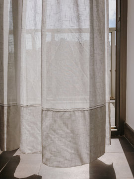 Sunlight shining through white curtain in open window