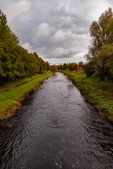 Looking downstream from above a river with Autumnal trees lining both side of the river bank