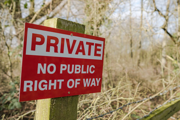 Newly fitted Private sign seen attached to a wooden post and barbed wire. Used to warn the public not to enter private land.