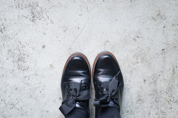 Black leather shoes. A pair of vintage fashion leather shoes for lady on the concrete floor, top view.