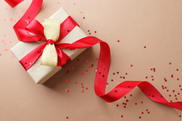 Craft gift box on a brown background, decorated with a textured bow and feathers, creating a...
