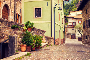Fototapeta na wymiar Old small stone street in Italy. City of Ranzo province of Trento. The foreground in focus, the background is blurred