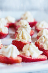 Stuffed strawberries filled with cheesecake filling made with whipped cream and cream cheese. Sprinkled with graham cracker crumbs. Selective focus with blurred foreground and background.