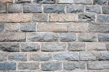 A wall of rough granite bricks with cement grout between them