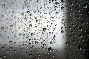 Drops of water on the glass against a blurred dark light gradient background on a rainy cloudy day....