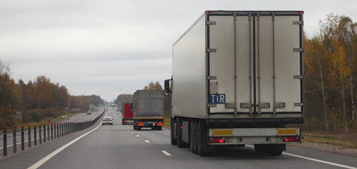 Cargo logistics, goods delivery on road transportation - dirty white European semi truck with TIR sign (Transports International Routiers)  moving on a two-lane asphalted country road in autumn day