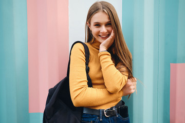 Attractive cheerful casual student girl happily looking in camera over colorful background - obrazy, fototapety, plakaty