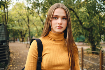 Portrait of attractive student girl confidently looking in camera in park