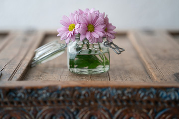 Beautiful flowers in a glass on a wooden cabinet in used look