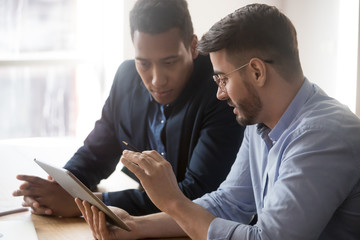 Diverse millennial employees discussing data report at office