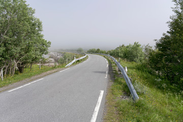 Fototapeta na wymiar small road bending into fjord fog near Grunnfor, Norway