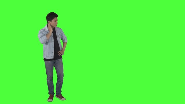 Full length of confused handsome man thinking something while walking to and fro in the studio. Shot in 4k resolution with green screen background