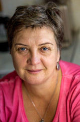 Mature woman in red sits at the window