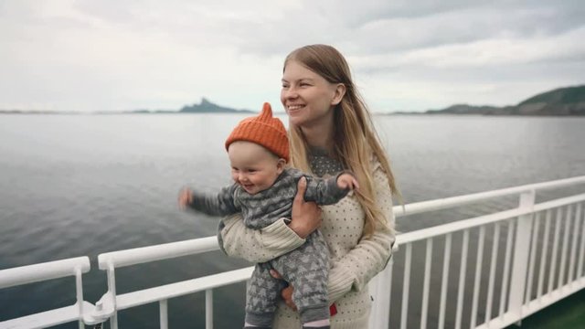 Mother traveling with baby by ferry family lifestyle mom holding infant child vacations outdoor in Norway maternity concept Mothers day