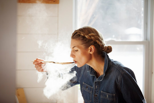 Woman tasting food while cooking in kitchen