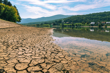 Dry cracked soil on the drying up watering place bank with animal tracks